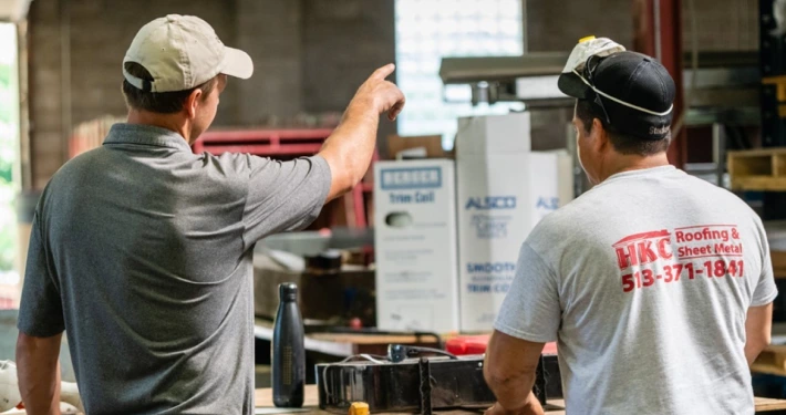 Two HKC Roofing workers reviewing roofing materials and supplies in a warehouse