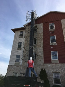 HKC Roofing crew member in a branded shirt operating debris removal equipment during a commercial roof maintenance project in Louisville, KY.
